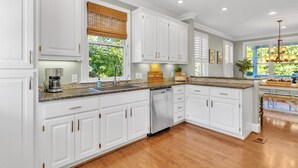 A spacious kitchen with white cabinetry, granite countertops, and a built-in dishwasher.