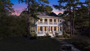 A two-story house with a porch, a flag, and a driveway.
