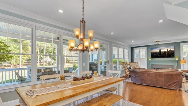 A spacious living room with a wooden dining table, white chairs, and a brown sofa.