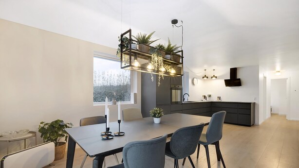 Ett modernt matområde med ett bord, stolar och en hängande lampa.