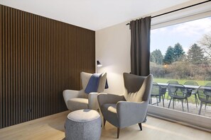A modern living room with a large window, a wooden slatted wall, and a view of the outdoors. - Beautiful newly renovated summer house by the sea (Frørup)