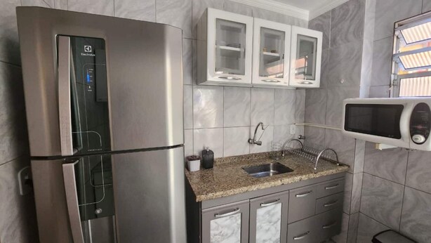 Eine Küche mit einem Edelstahlkühlschrank, einer Spüle mit Granitablage und weißen Schränken.