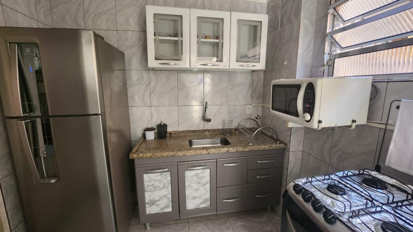 A compact kitchen with a stainless steel refrigerator, a microwave, and a gas stove.