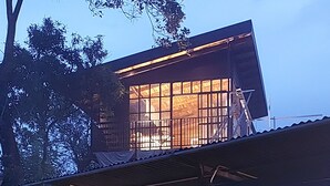 A two-story building with a balcony on the upper floor. The ground floor has large windows and a sign that reads "Live to Ride." There are chairs and a table outside. - Sitting on stilts, Stuido Wow has spectacular volcano, lake & rain forest views! (El Castillo)