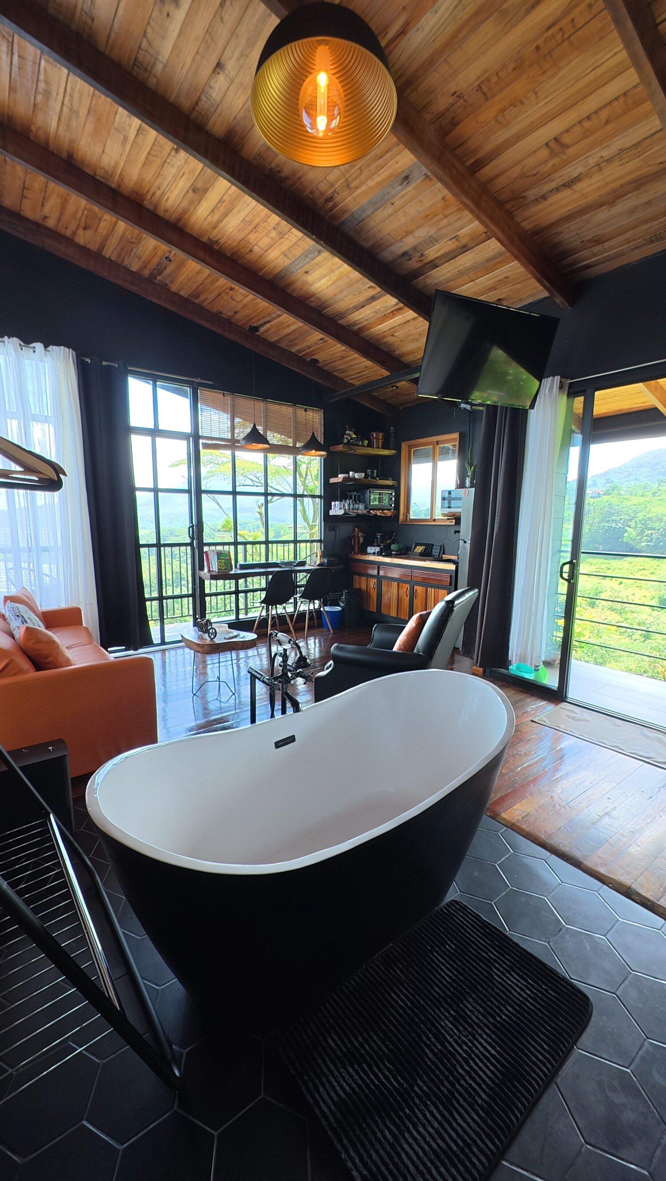 A modern bathroom with a freestanding bathtub, a large mirror, and a view of the outdoors.