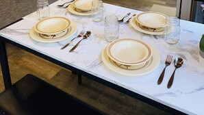 Ruokailutila, jossa on neljälle katettu ruokapöytä, mukaan lukien lautaset, aterimet ja lasit.