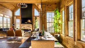 A spacious living area with a wooden interior, a fireplace, and large windows. - New to VRBO!  Theater Seating, Pool Table, Gaming Station, Bunk Rm, Hot Tub (Gatlinburg)