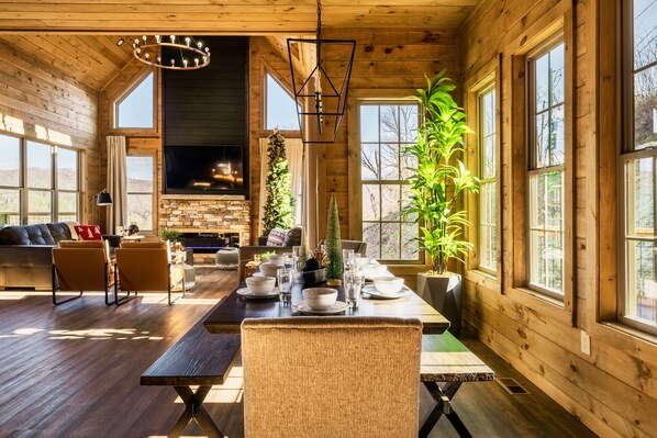 Un vaste espace de vie doté d’un intérieur en bois, d’une cheminée et de grandes fenêtres.
