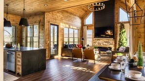 A spacious kitchen with a large island, wooden walls, and a stone fireplace. - New to VRBO!  Theater Seating, Pool Table, Gaming Station, Bunk Rm, Hot Tub (Gatlinburg)