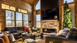 A cozy living room with a fireplace, leather sofas, and a large TV. - New to VRBO!  Theater Seating, Pool Table, Gaming Station, Bunk Rm, Hot Tub (Gatlinburg)