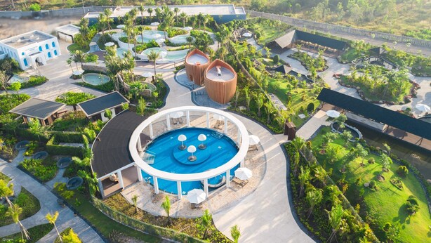 An aerial view of a resort with multiple swimming pools, lush greenery, and a variety of buildings. - Happy Stay Resort (Ho Chi Minh City)