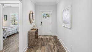 A hallway with a white door, a small console table with a candle, and a framed picture on the wall. - Sunset Haven by the Pool (Panama City Beach)