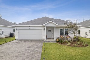 A single-story house with a garage, a front porch, and a well-maintained lawn. - Sunset Haven by the Pool (Panama City Beach)