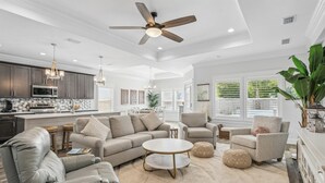 A modern living room with a sofa, armchairs, a coffee table, and a ceiling fan. - Sunset Haven by the Pool (Panama City Beach)