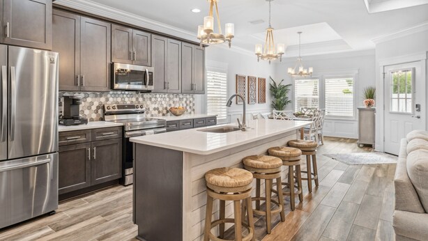 A modern kitchen with stainless steel appliances, a large island with stools, and pendant lighting. - Sunset Haven by the Pool (Panama City Beach)