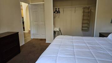 A bedroom with a large bed, a wardrobe, and a door leading to another room.