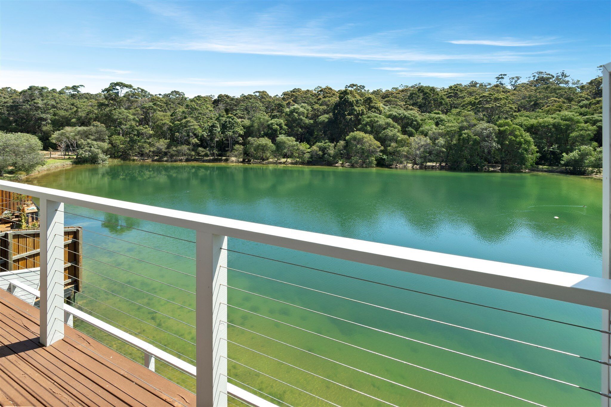 A deck with a clear view of a lake surrounded by dense trees.