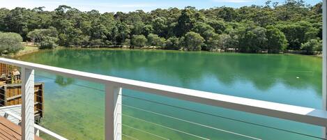 A deck with a clear view of a lake surrounded by dense trees.