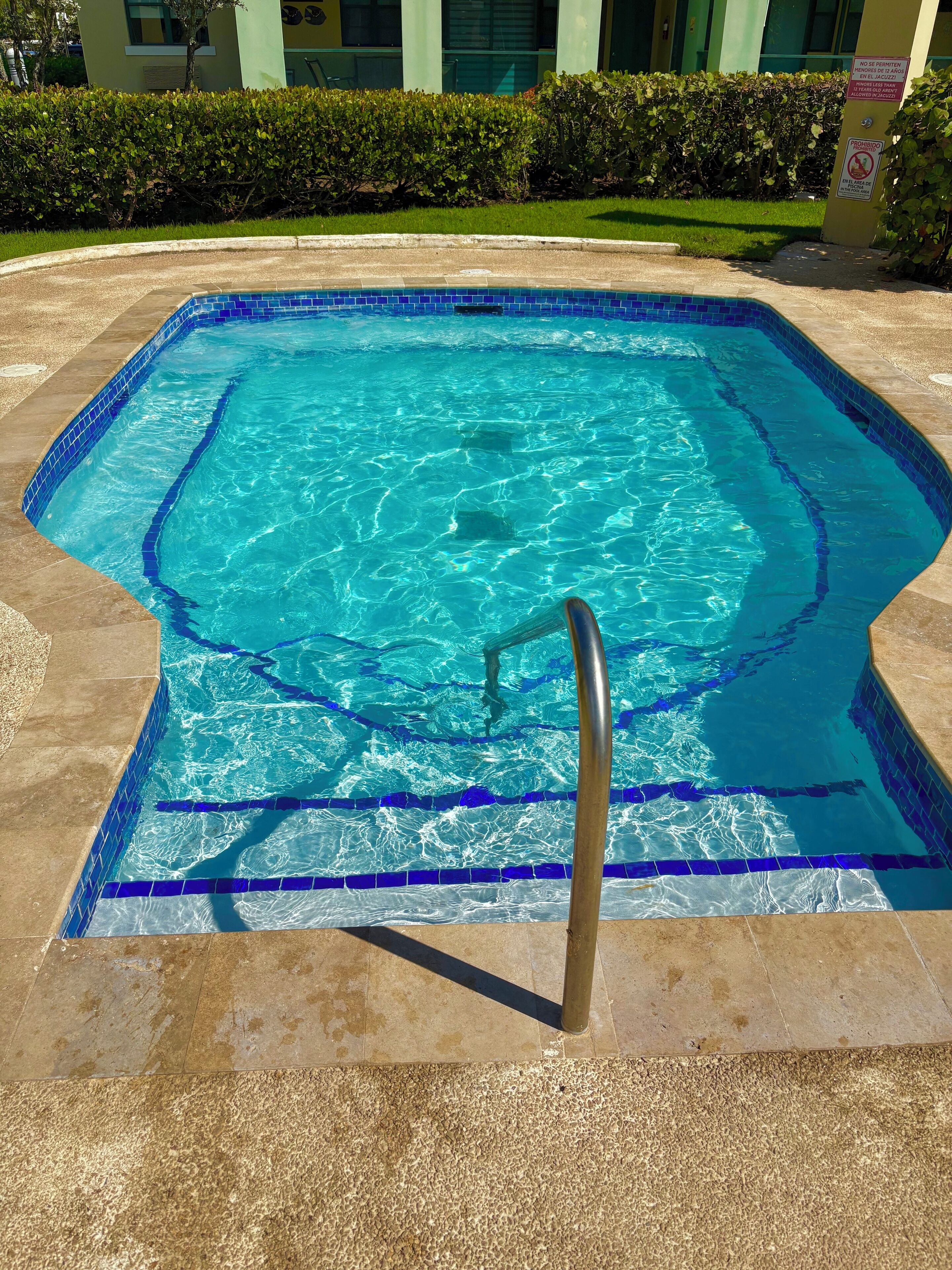 A swimming pool with a tiled edge and a metal ladder.