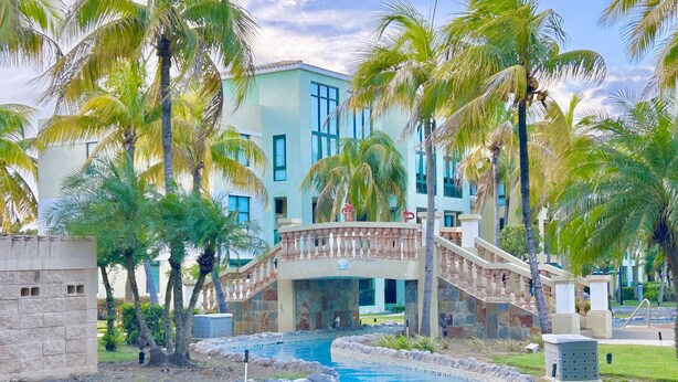 Ein Resort mit Pool, Palmen und einer Brücke.