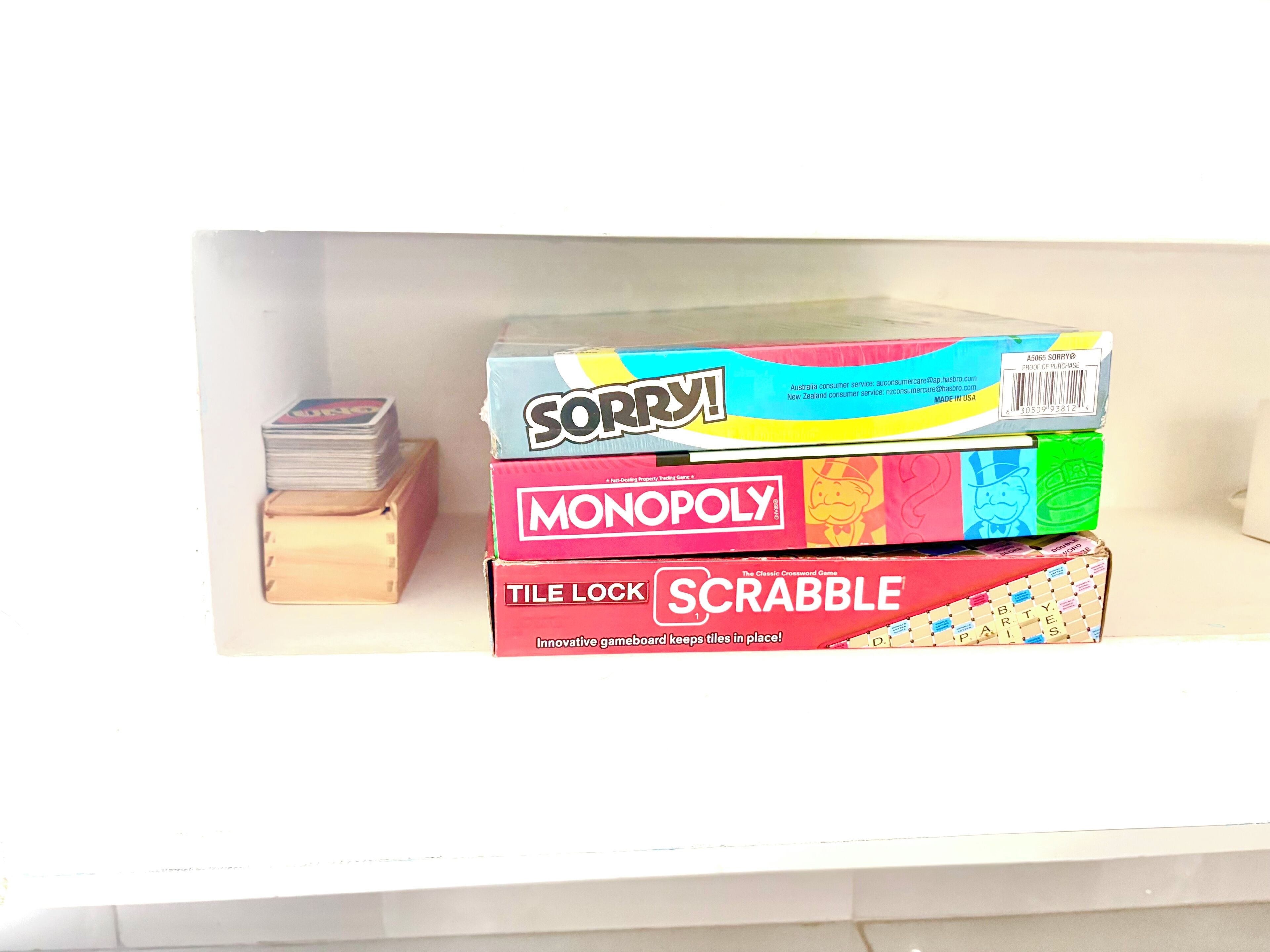 Une étagère avec quatre jeux de société : Sorry !, Monopoly, Tile Lock et Scrabble.