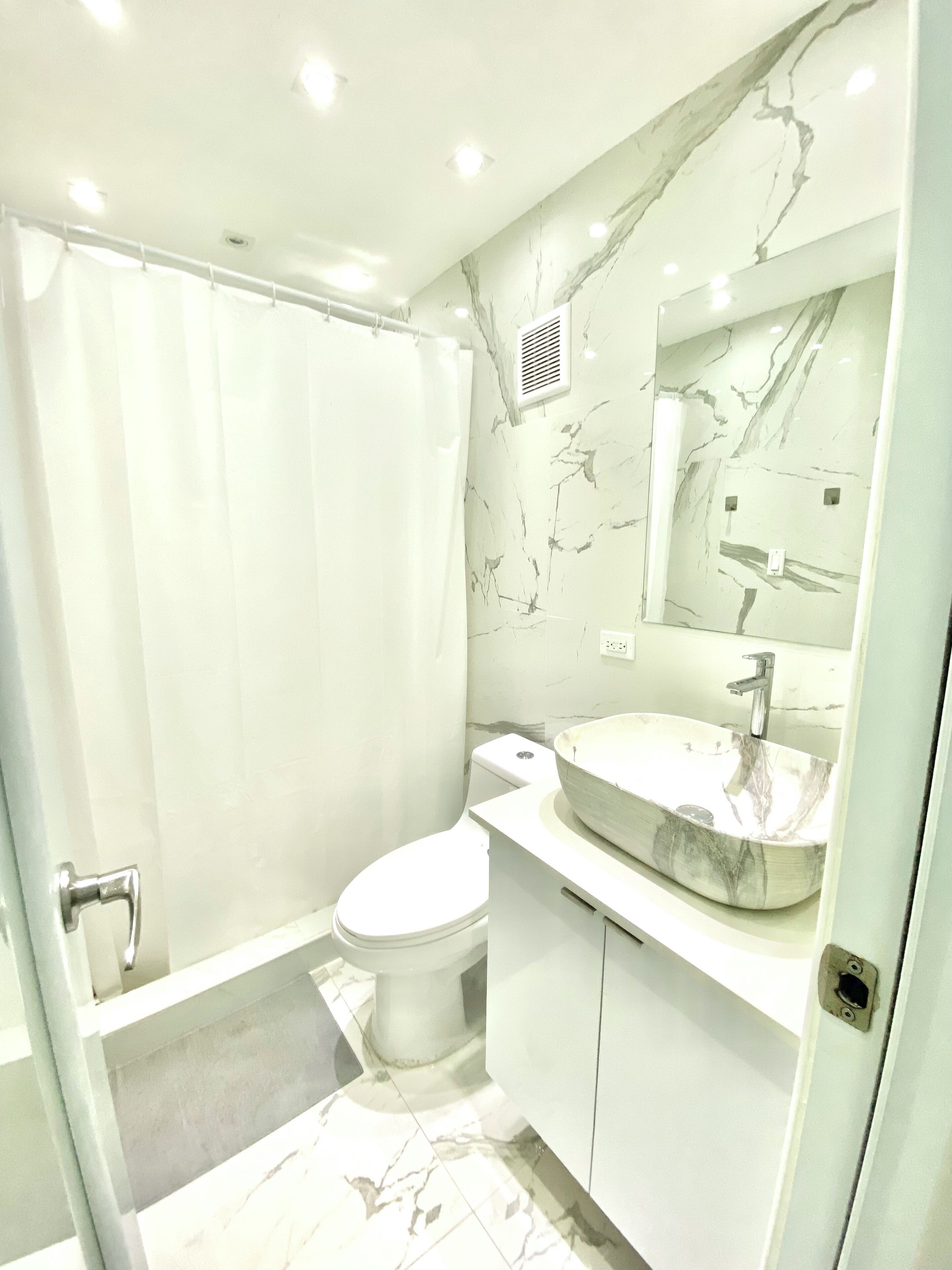 Ein modernes Badezimmer mit Marmorwaschtisch, Toilette und Duschbereich.