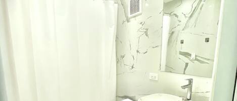 Ein modernes Badezimmer mit Marmorwaschtisch, Toilette und Duschbereich.