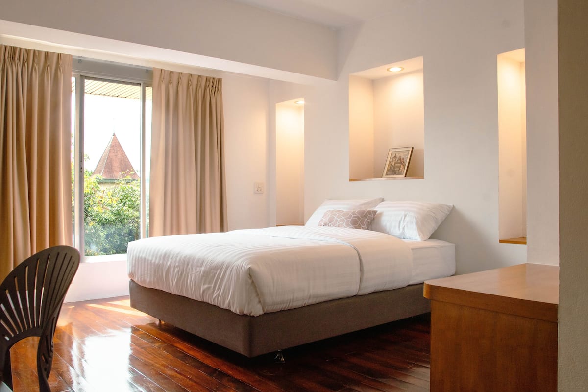 A bedroom with a bed, a chair, and a desk.