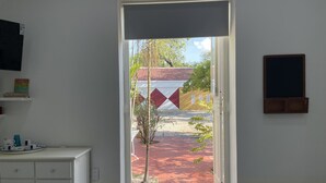 A doorway leading to an outdoor area with a tiled floor, a small tree, and a building with a red roof.
