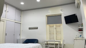 A bedroom with a bed, a desk, a chair, a TV, and a wardrobe.