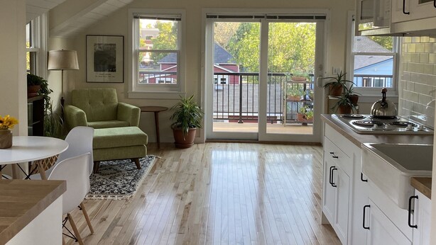 A spacious kitchen with white cabinets, a wooden ceiling, and a large window overlooking a residential area. - Old Town Oasis - the perfect 30 day stay (Fort Collins)