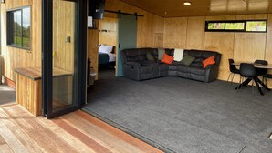 A modern interior with a wooden exterior, a sectional sofa, and a dining area.