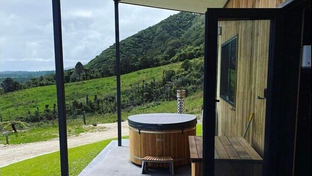 A wooden deck with a hot tub and a view of a green landscape.