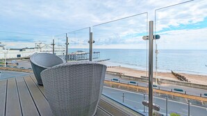 A balcony with wicker chairs overlooking a beach and a pier. - West Lodge, Bognor Regis -  a flat that sleeps 4 guests  in 2 bedrooms (Bognor Regis)