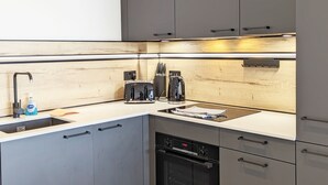 A modern kitchen with grey cabinets, a wooden backsplash, a sink, a toaster, and a dishwasher. - West Lodge, Bognor Regis -  a flat that sleeps 4 guests  in 2 bedrooms (Bognor Regis)