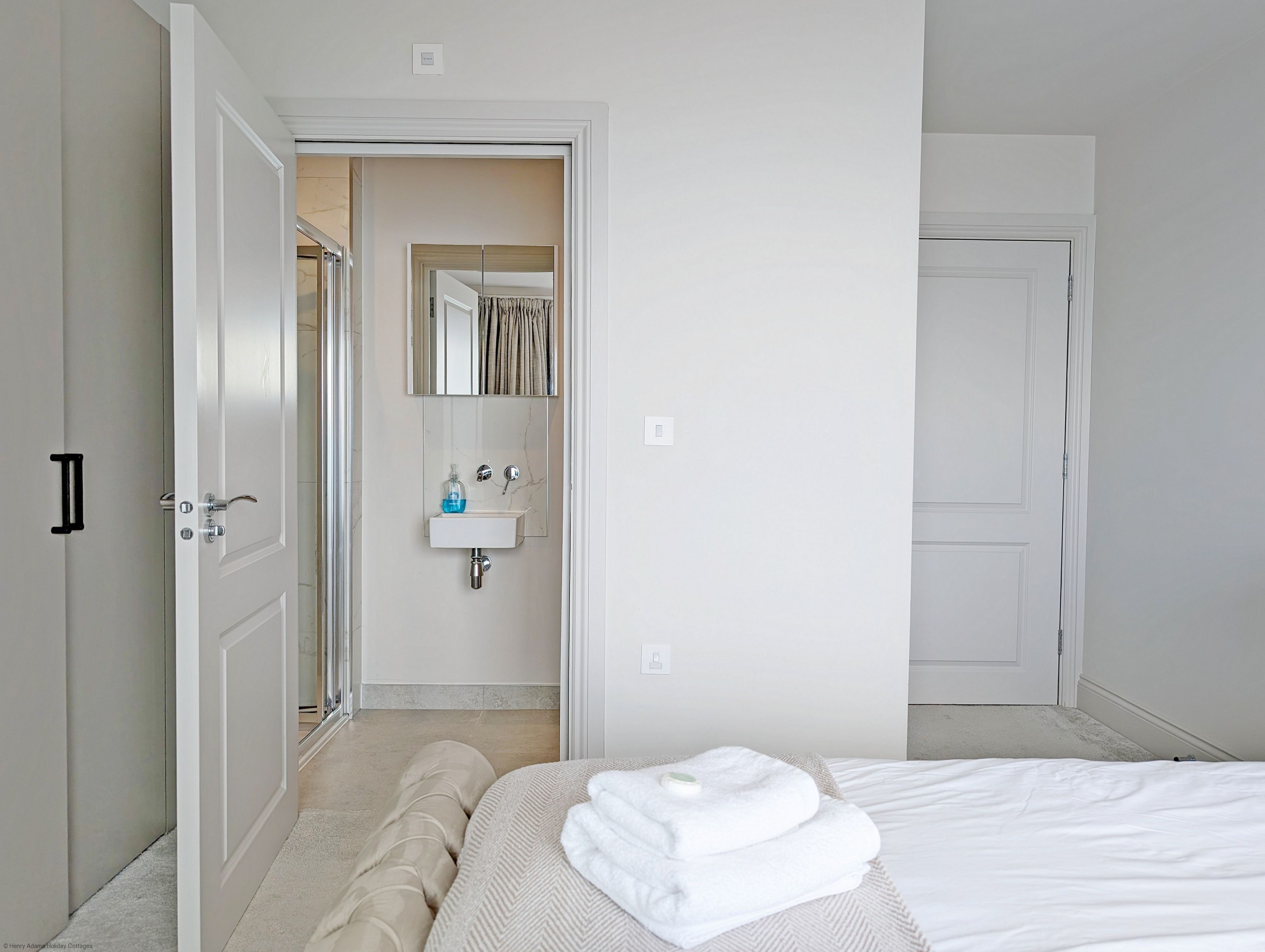 Ein Hotelzimmer mit einem Bett, einem Badezimmer mit Waschbecken und Spiegel sowie einer Tür zu einem weiteren Raum.