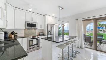 A modern kitchen with white cabinets, stainless steel appliances, and a large island with bar stools.