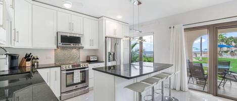 Una cocina moderna con armarios blancos, electrodomésticos de acero inoxidable y una isla grande con taburetes de bar.