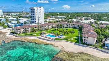 Un resort con varias construcciones, un área de piscina central y una playa.