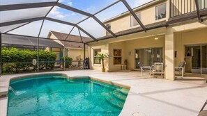 A covered swimming pool area with a patio and lounge chairs. - South facing pool home, gated community, 10 mins to Walt Disney World Resort! (Kissimmee)