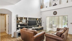 Un salon moderne avec des canapés en cuir, une table basse en verre et un meuble de rangement noir agrémenté d’objets décoratifs.