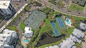 An aerial view of a property with a tennis court, swimming pools, and a landscaped area with palm trees. - Beautiful 3BR Siesta Key Condo - beach access - GBB 1350 (Sarasota)