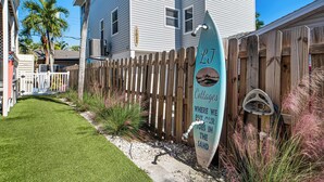 A wooden fence, a sign with 'Cottages' and a beach scene, and a building in the background. - LJ's Cottages 4 BALCONY BEACH AND POOL (Sarasota)