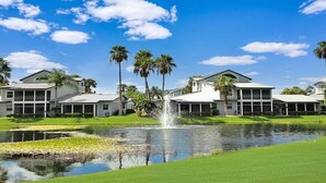 A residential area with houses, a pond, and palm trees.