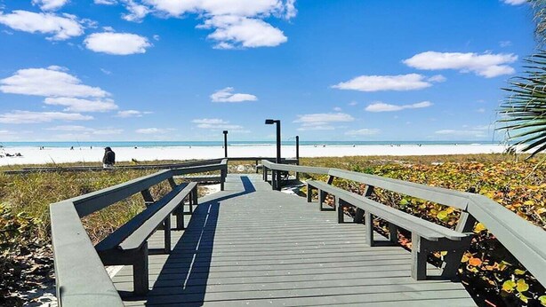 A wooden boardwalk leading to a beach with clear skies.