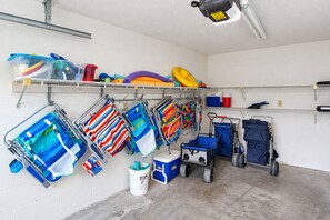 A storage area with shelves holding various items including colorful beach towels, a cooler, and a small cart.