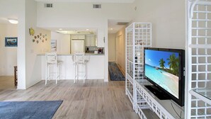 A modern living room with a flat-screen TV, a kitchen area, and a dining space. - Bayfront 2br Siesta Key condo with beach access - GBB 1382 (Sarasota)
