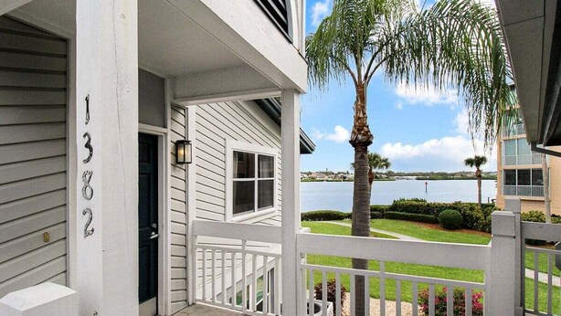 A two-story house with a white exterior, a porch with a white railing, and a view of a lake. - Bayfront 2br Siesta Key condo with beach access - GBB 1382 (Sarasota)