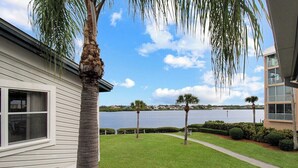 A residential property with a view of a lake, a well-maintained lawn, and a tall palm tree. - Bayfront 2br Siesta Key condo with beach access - GBB 1382 (Sarasota)