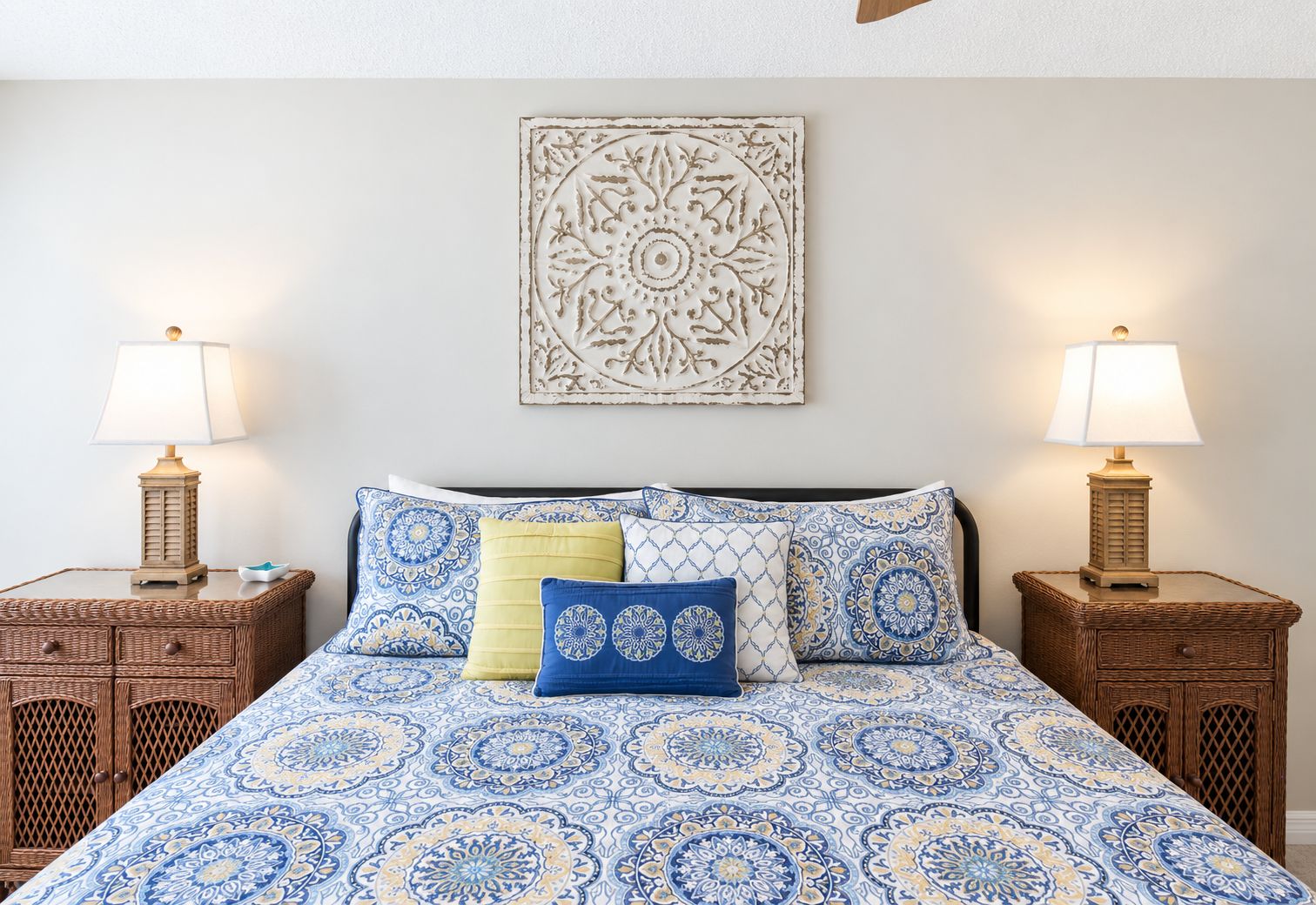 A bed with a patterned bedspread, two nightstands with lamps, and a decorative wall piece.